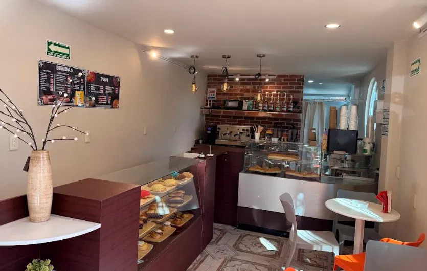 Interior de Café con Cereza: vitrina con pan dulce, barra de madera vino, pared de ladrillo y lámparas colgantes